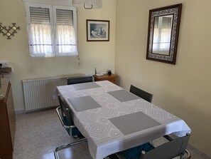 Enjoy meals at the dining table, flanked by two chairs, with a decorative mirror and artwork on the walls.