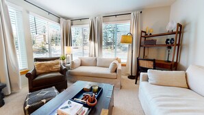 A living room with a sofa, armchair, coffee table, and bookshelf. - Bright Upgraded Modern Wash/Dryer Near Bike & Walking Trails Pool On-site (Mammoth Lakes)