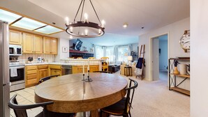 A modern kitchen with wooden cabinets, a central island, and a dining area with a round table and chairs. - Bright Upgraded Modern Wash/Dryer Near Bike & Walking Trails Pool On-site (Mammoth Lakes)
