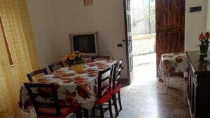 A dining area with a table set for four, a television, and a door leading outside.