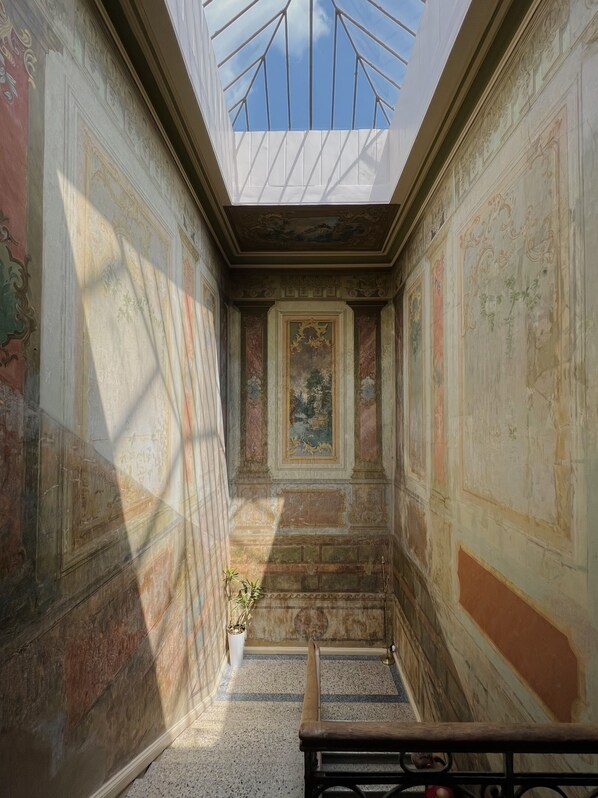 A narrow corridor with a skylight, ornate walls, and a central painting. - Unfound Door (Tbilisi)