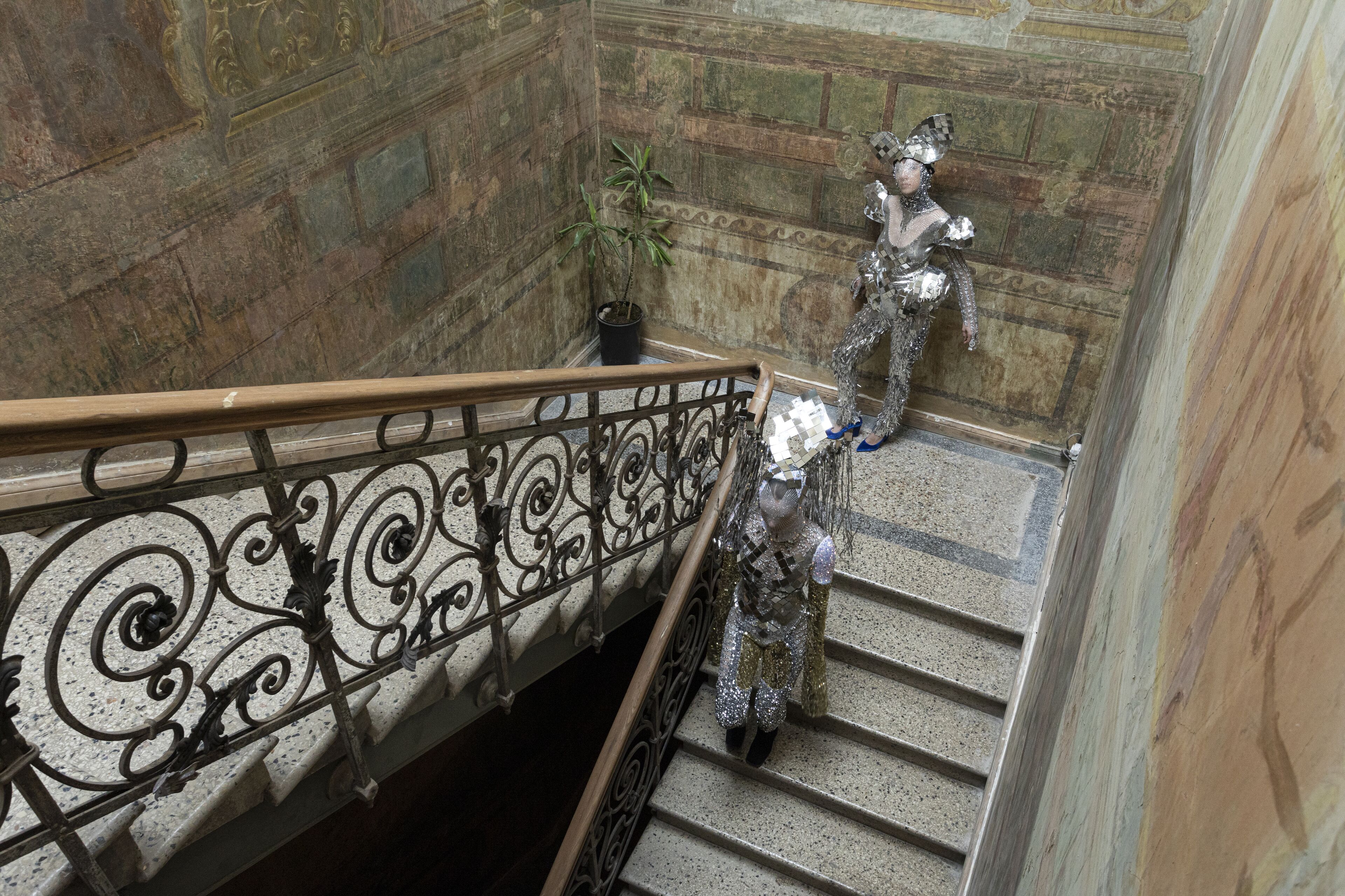 Uma escadaria com grades de metal ornamentadas e uma estátua.