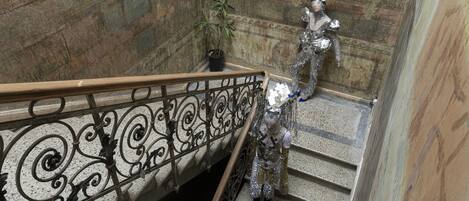 Uma escadaria com grades de metal ornamentadas e uma estátua.