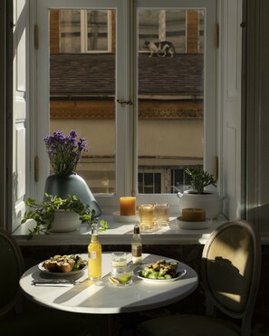 A dining table with plates of food, a vase of flowers, candles, and a bottle of wine. - Unfound Door (Tbilisi)