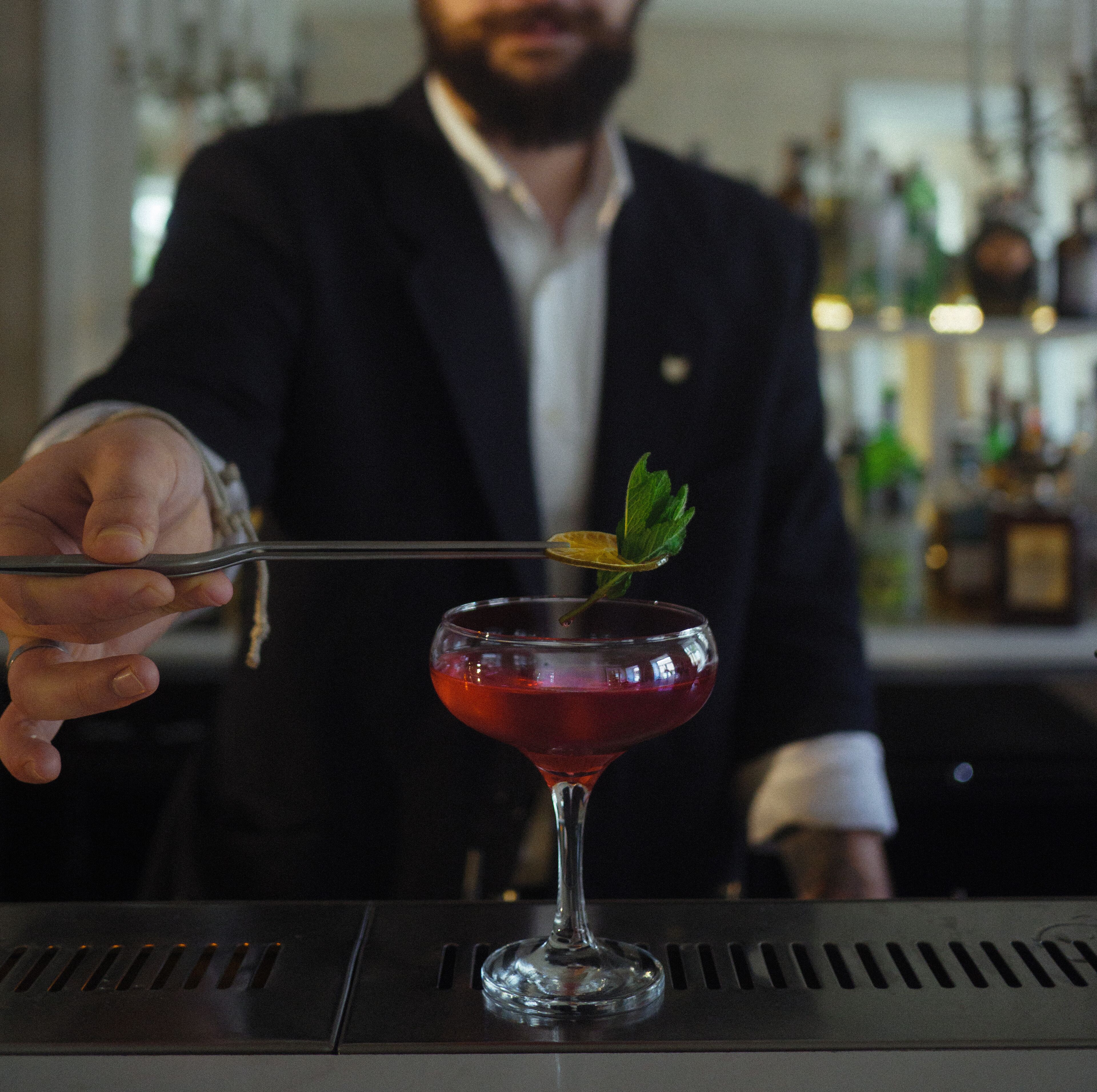 A bartender holding a cocktail shaker with a garnish.