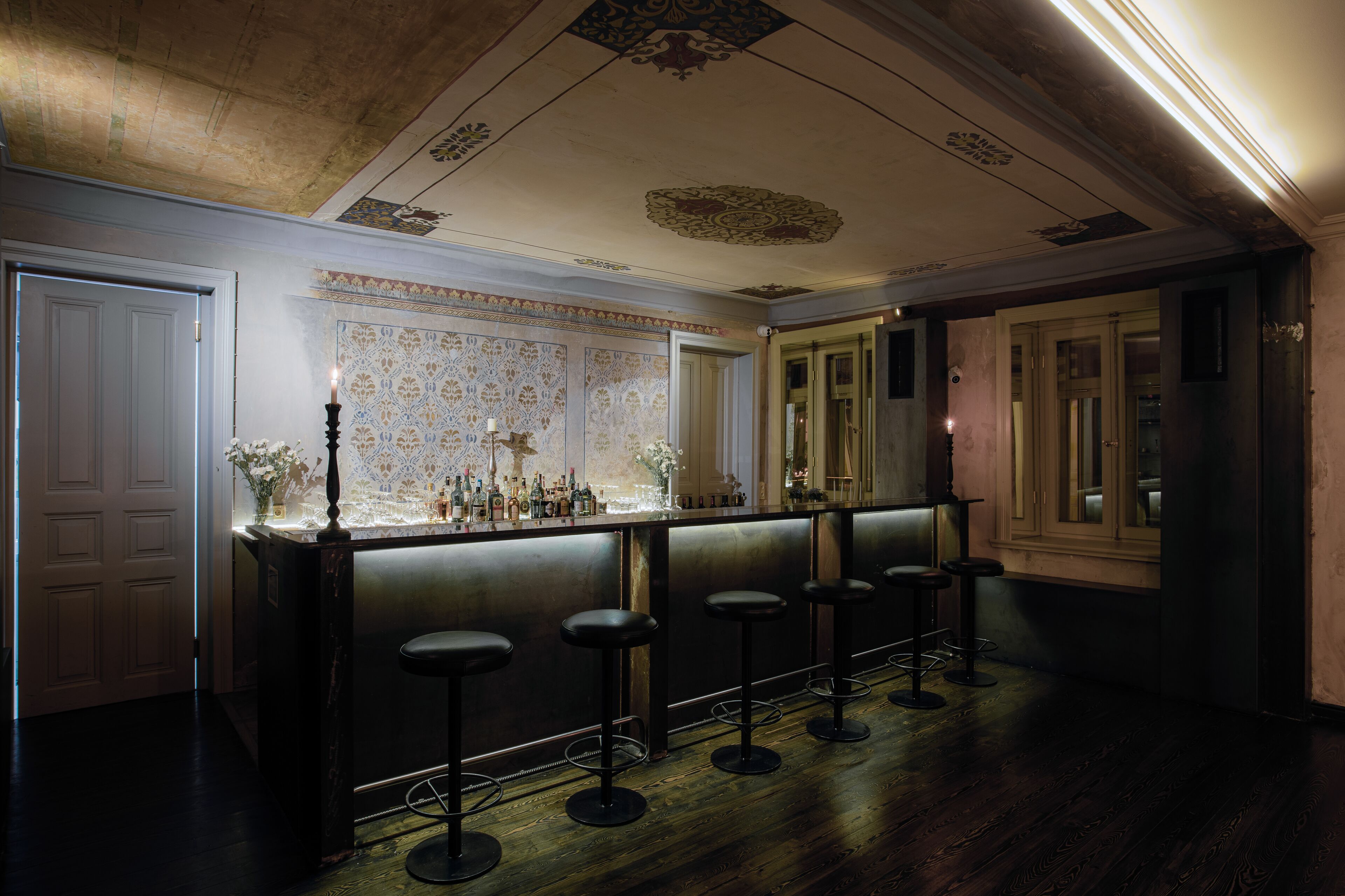 Un espace bar avec un comptoir, des tabourets et un plafond décoratif.