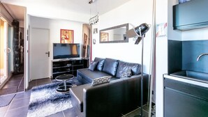 A modern living room with a sofa, TV, and a large mirror.