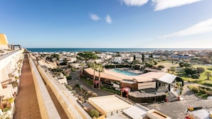 A resort with a pool, a beach bar, and a view of the sea.