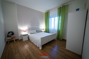 A bedroom with a bed, a nightstand, a chair, and a wardrobe.
