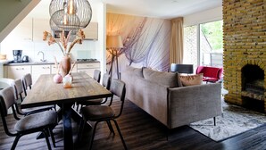 Un salon moderne avec une table à manger en bois, un canapé gris et une cheminée en briques.