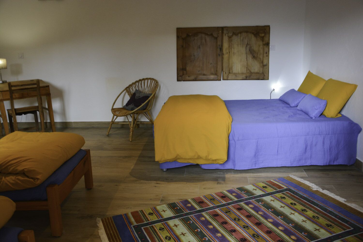 A bedroom with a bed, a chair, a small table, and a rug.