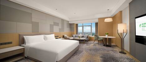 A hotel room with a large bed, a sofa, a small table, and a TV screen displaying a message.