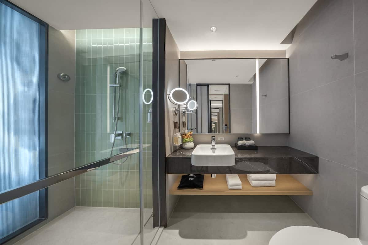 Une salle de bain moderne avec une douche à parois de verre, un lavabo avec un miroir et des toilettes.