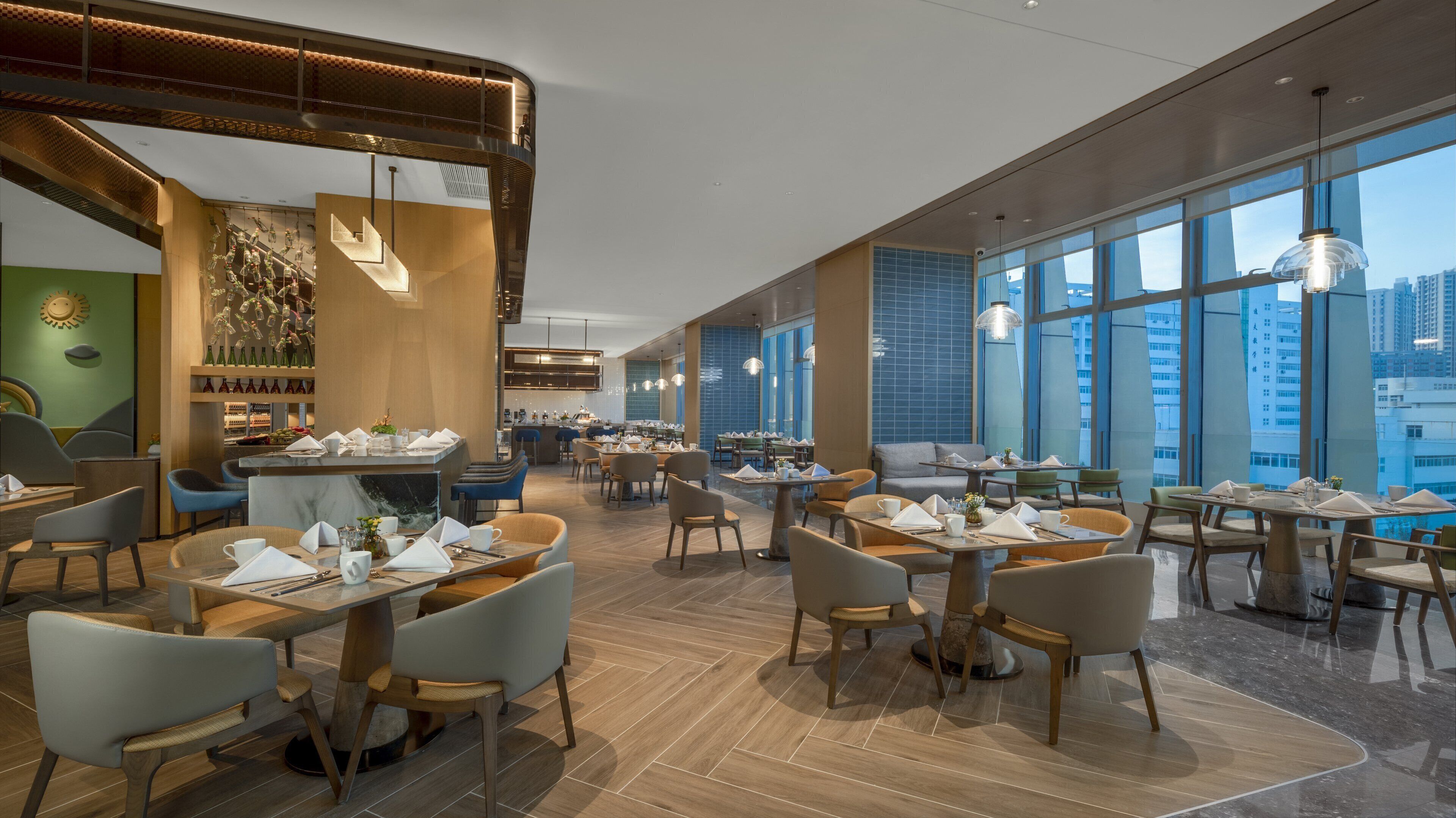A modern restaurant with high ceilings, large windows, and a variety of seating arrangements.