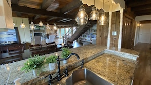 A kitchen with granite countertops, a stainless steel sink, and hanging pendant lights. - Secluded Lakefront Chalet  (Grass Lake)