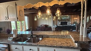 A kitchen with granite countertops, white cabinetry, and a stone fireplace. - Secluded Lakefront Chalet  (Grass Lake)