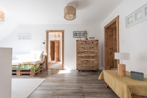 A bedroom with a bed, wooden dresser, and a lamp on a table.