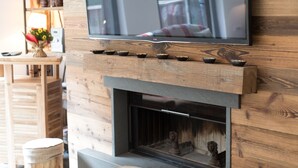 A flat-screen TV mounted on a wooden wall above a fireplace with a mantel.