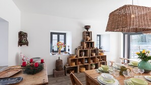 A dining area with a wooden table set for four, surrounded by shelves of pottery and decorative items.