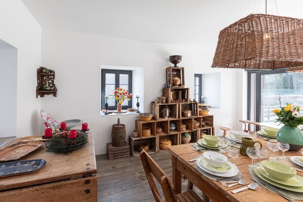 A dining area with a wooden table set for four, surrounded by shelves of pottery and decorative items.