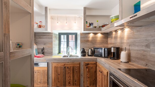 A modern kitchen with wooden cabinets, a built-in oven, and a microwave.