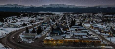 Une ville recouverte de neige, sous un ciel étoilé, et entourée de montagnes.