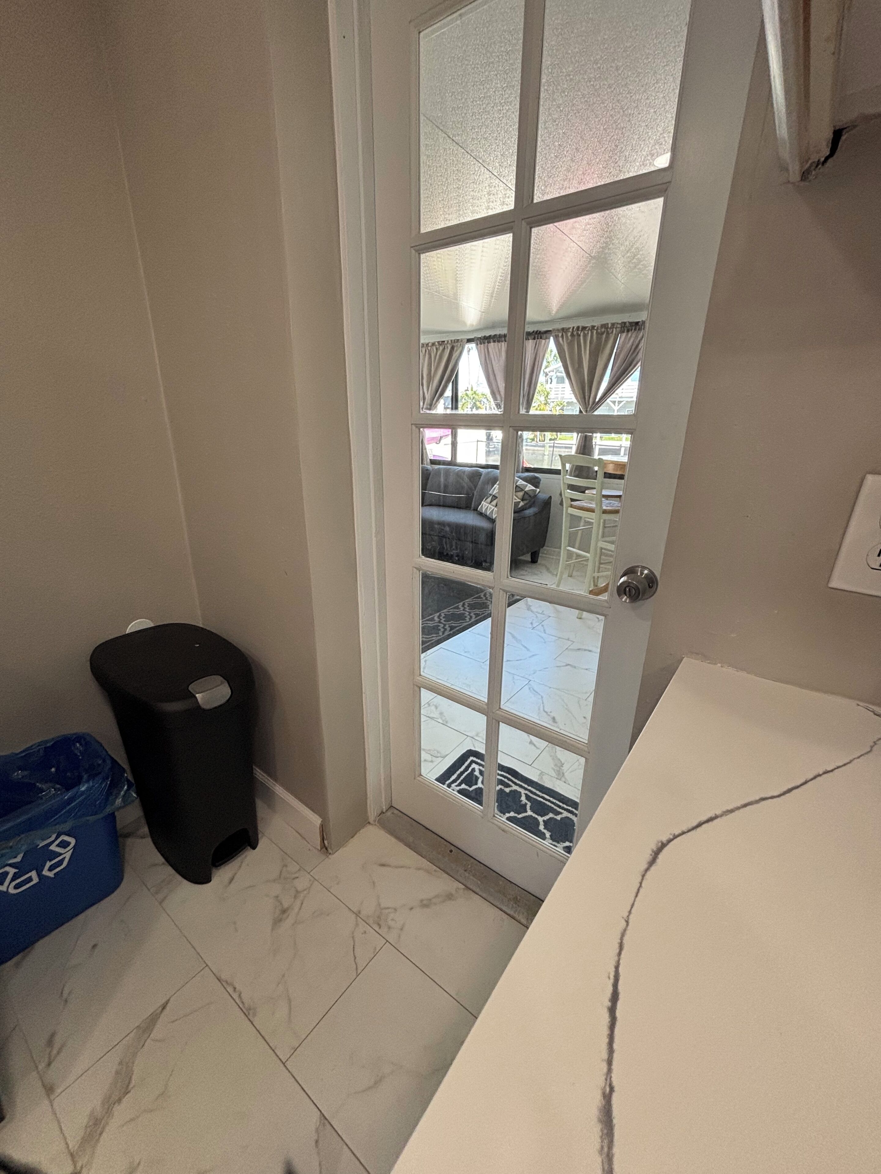 Une salle de bain avec un lavabo blanc, une poubelle noire et un sac en plastique bleu sur le sol.