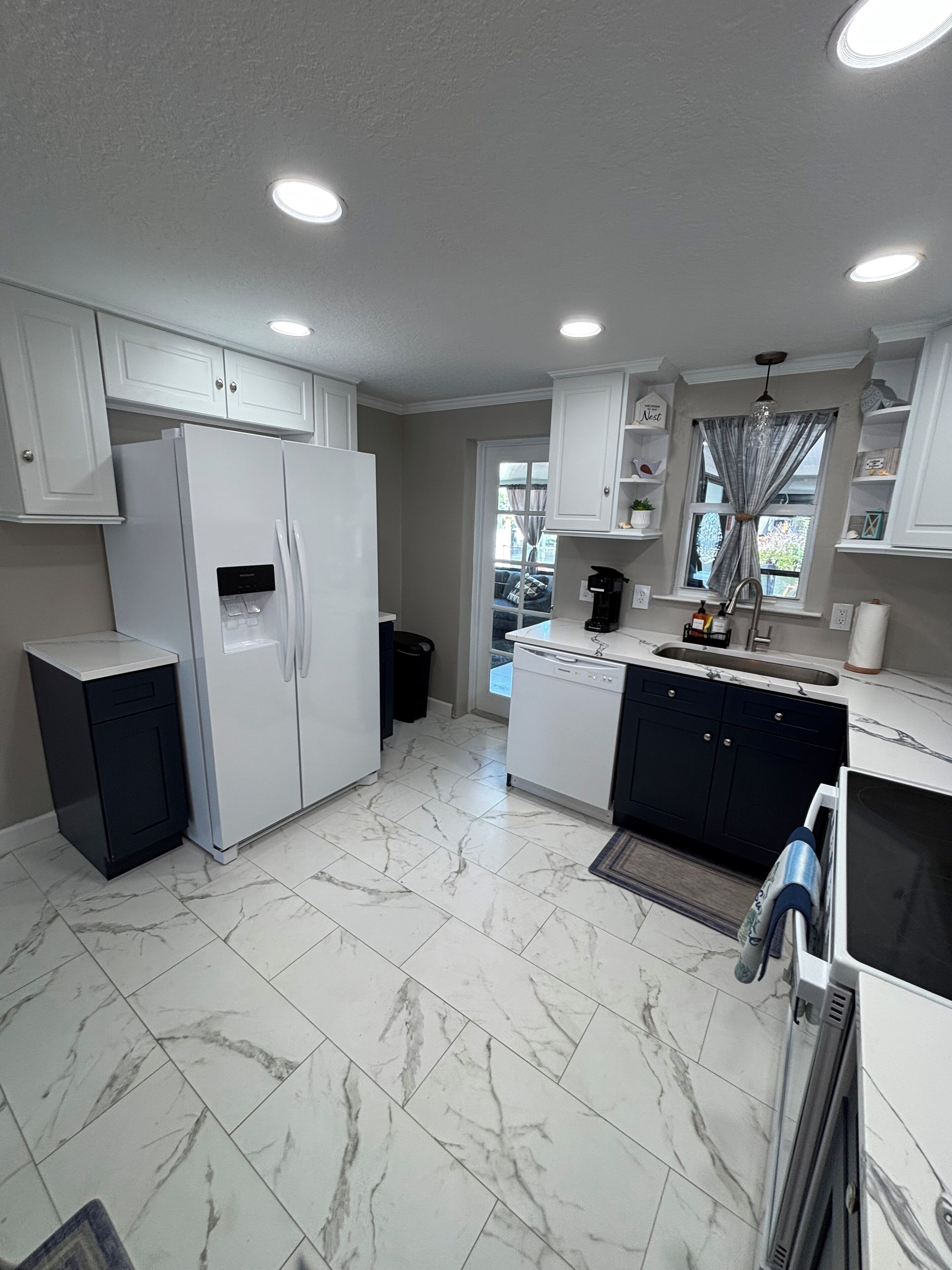 A modern kitchen with white cabinets, a built-in refrigerator, a dishwasher, and a sink.