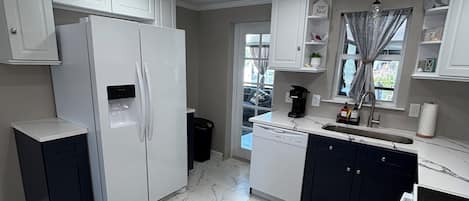 A modern kitchen with white cabinets, a built-in refrigerator, a dishwasher, and a sink.