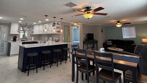 A spacious kitchen with a central island, bar stools, and a dining area with a table and chairs.