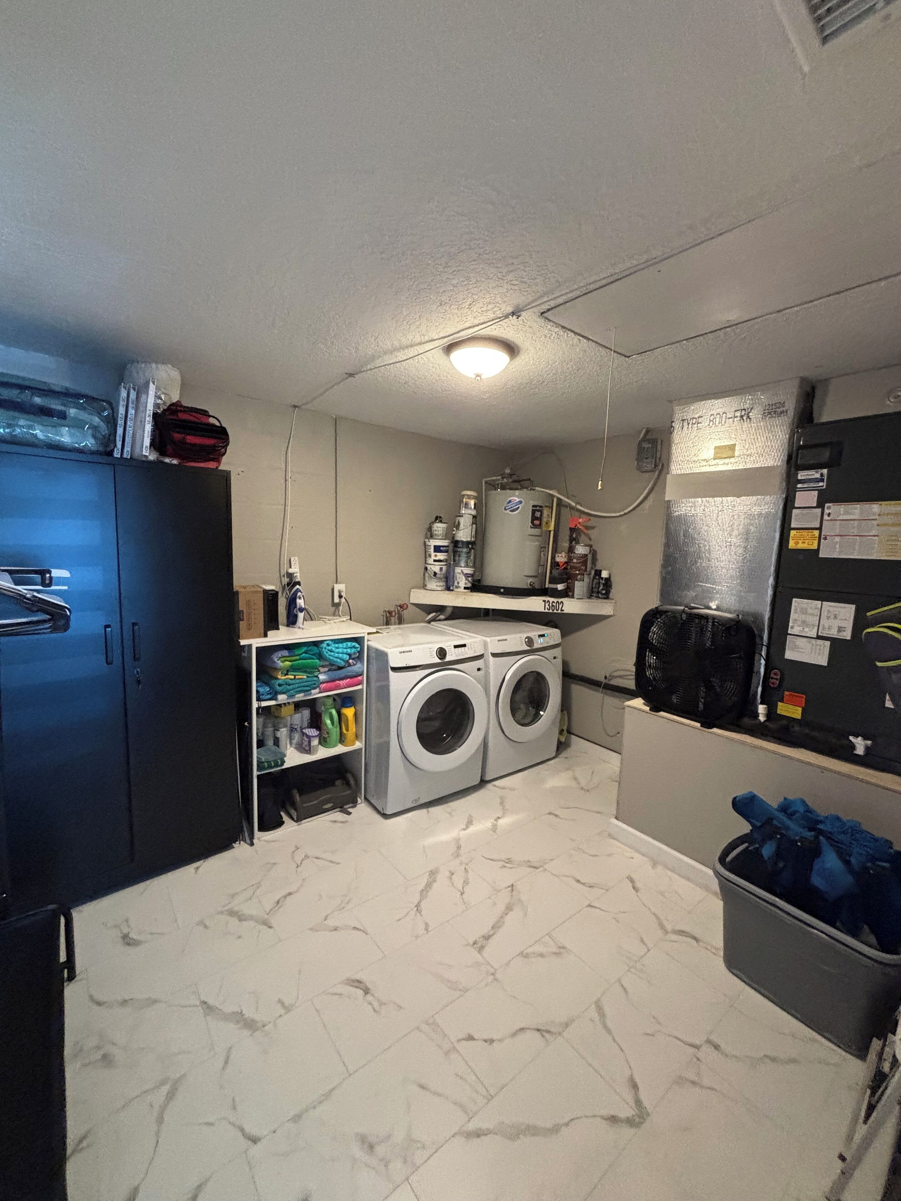 A laundry room with two front-loading washing machines, a water heater, and a refrigerator.