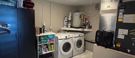 A laundry room with two front-loading washing machines, a water heater, and a refrigerator.