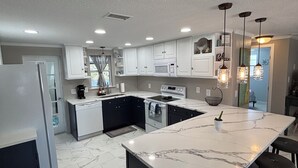 A modern kitchen with white cabinets, a large island with bar stools, and pendant lighting.