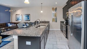 A modern kitchen with granite countertops, stainless steel appliances, and a built-in island. - Spacious and Luxurious Home With Splash Pool, Close to Disney #4st804 (Kissimmee)