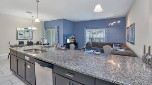 A modern kitchen with granite countertops, a built-in dishwasher, and a large island. - Spacious and Luxurious Home With Splash Pool, Close to Disney #4st804 (Kissimmee)