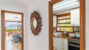 A modern kitchen with wooden cabinets, a built-in oven, and a view of the sea through a window. - Beautiful, 3 bedroom, ground floor, sea front property, large furnished terrace (Puerto de Pollensa)