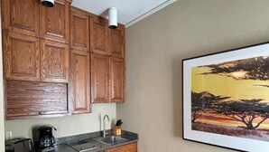 A compact kitchen with wooden cabinets, a countertop, and a coffee maker. - Powell Place at Nob Hill (San Francisco)