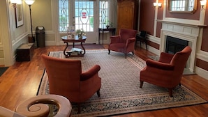 A spacious living area with a fireplace, two armchairs, a coffee table, and a patterned rug. - Powell Place at Nob Hill (San Francisco)