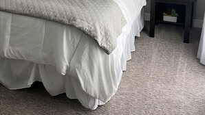 A neatly made bed with a quilted cover, two bedside lamps, a decorative wall piece, and a small plant on a bedside table. - Resort Living near Kierland and Mayo Clinic  (Scottsdale)