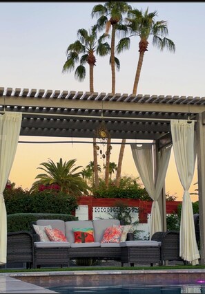 A covered seating area with a pool, surrounded by palm trees and a decorative wall. - Resort Living near Kierland and Mayo Clinic  (Scottsdale)