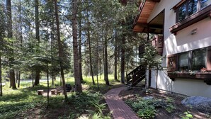 A forested area with a brick pathway leading to a building with a wooden staircase.