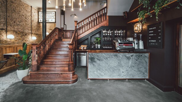 A staircase leading to a bar area with a marble counter and coffee machines. - The Pilgrm Hotel (London)