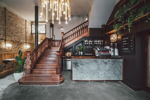 A staircase leading to a bar area with a marble counter and coffee machines. - The Pilgrm Hotel (London)