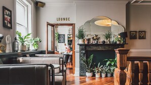 A lounge area with seating, a fireplace, and potted plants. - The Pilgrm Hotel (London)