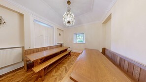 A room with a long wooden bench, a table, and a chandelier. - NEW Listing -  Fairytale Manor House with Indoor Swimming Pool (Swansea)