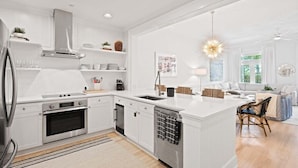 A modern kitchen with white cabinetry, stainless steel appliances, and a central island.
