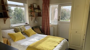 A bedroom with a bed, bedside tables, a window, and a door. - Entire 1bed Studio With Ensuite, Balcony & Parking (Westcliff-on-Sea)