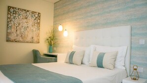 A hotel room with a large bed, a bedside table, a chair, a wall-mounted painting, and a hanging light fixture. - Alojamento Batata - Peixe Imperador  (Nazaré)