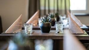 Una mesa de comedor con una planta en maceta en el centro, dos vasos y un reposa servilletas.