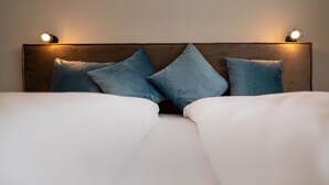 Una cama bien hecha con almohadas azules y dos lámparas de noche.